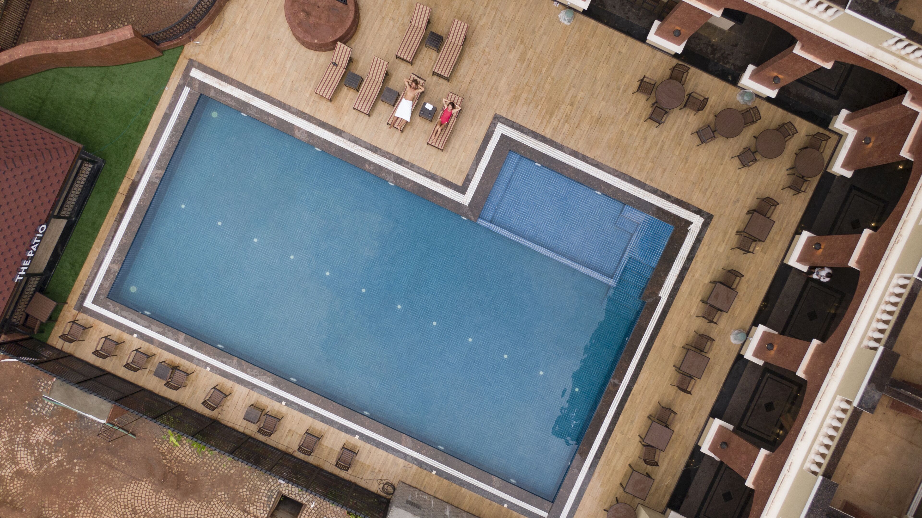 An aerial view of a swimming pool with lounge chairs and tables arranged around it.