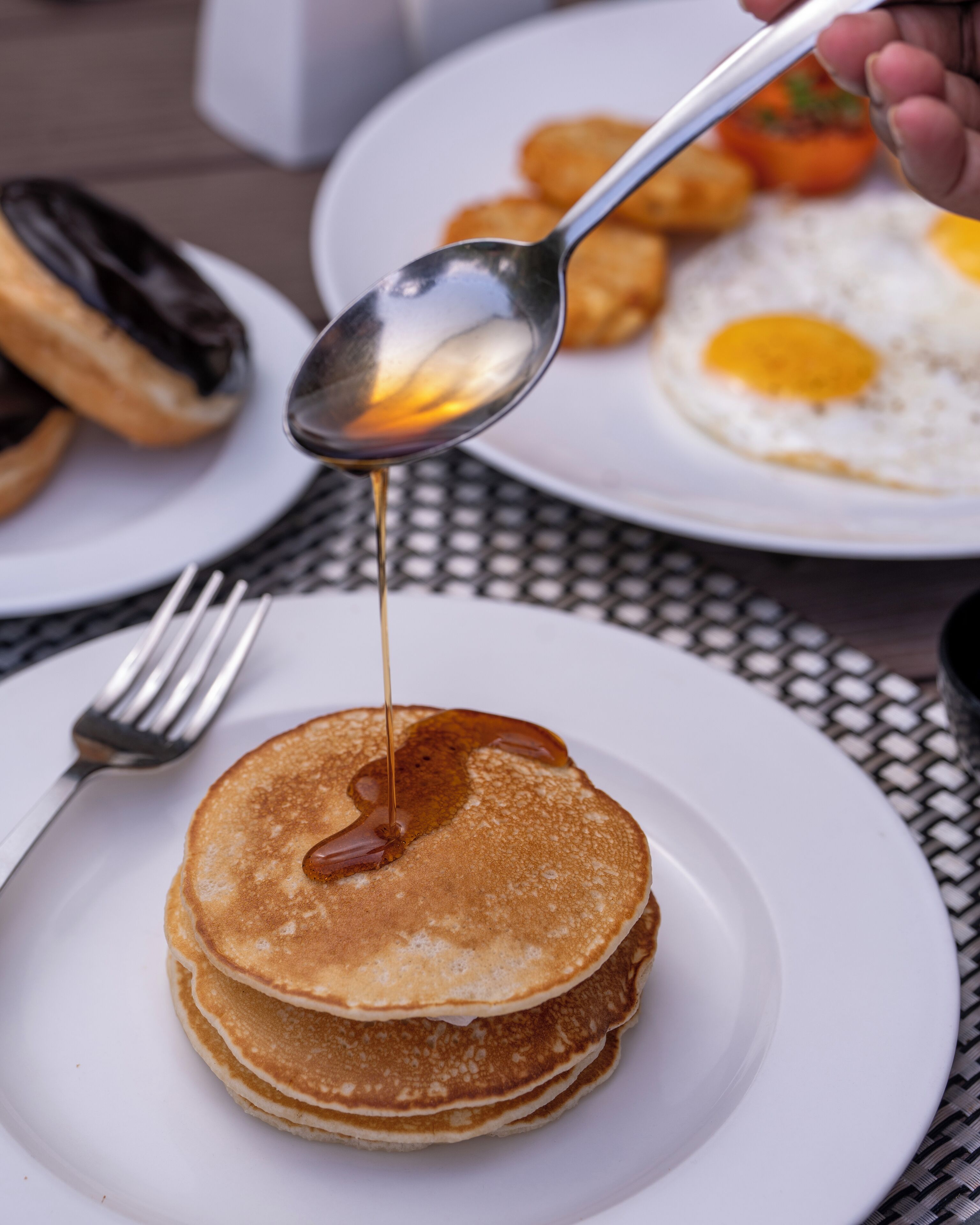 A stack of pancakes with syrup being poured on them.