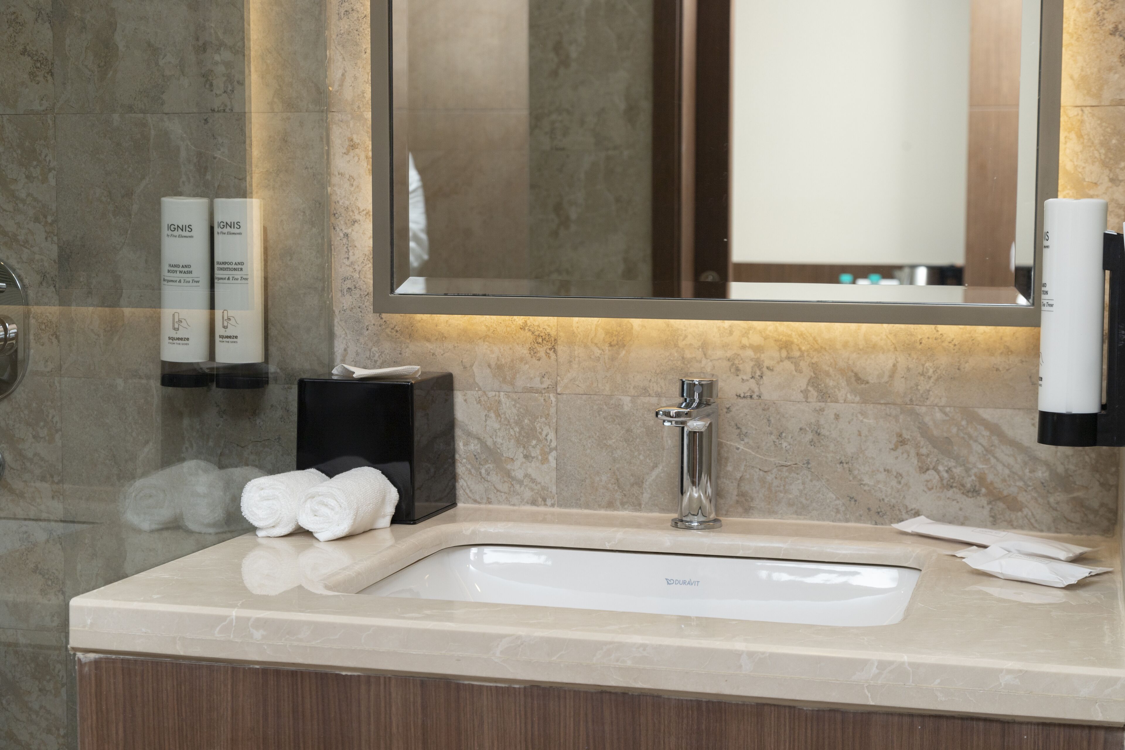 Une salle de bain avec un lavabo en marbre, un miroir et des articles de toilette fixés au mur.