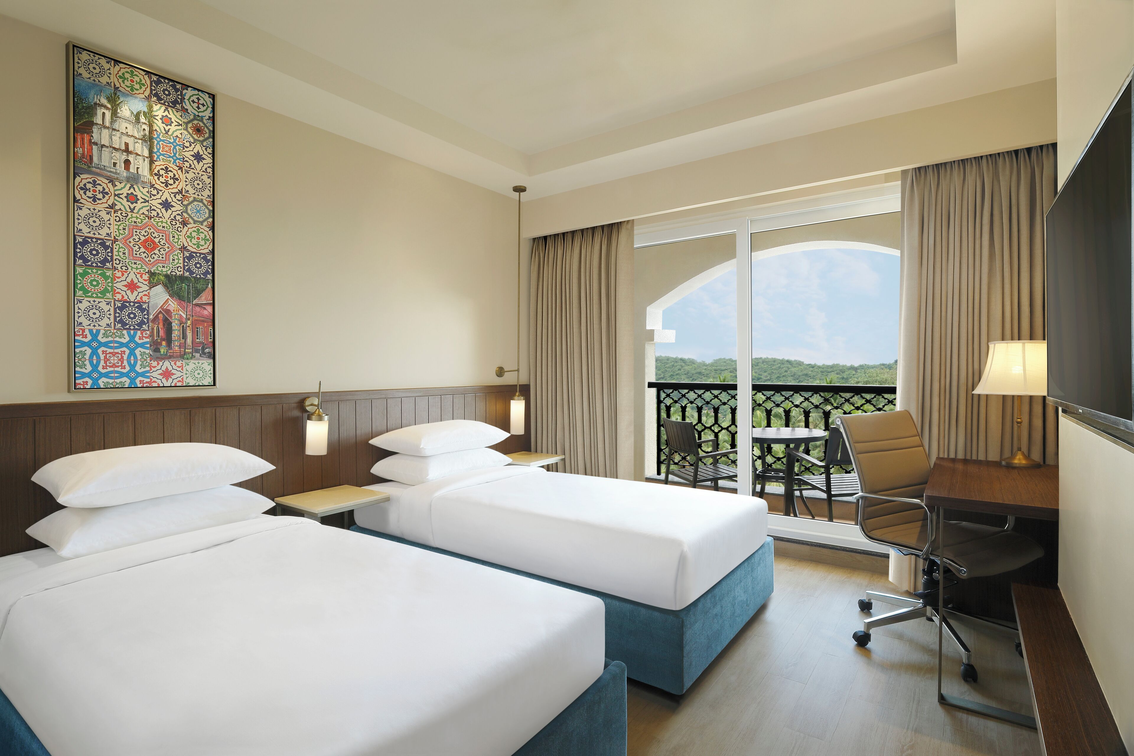 A hotel room with two beds, a desk, a chair, a TV, and a balcony with a view.
