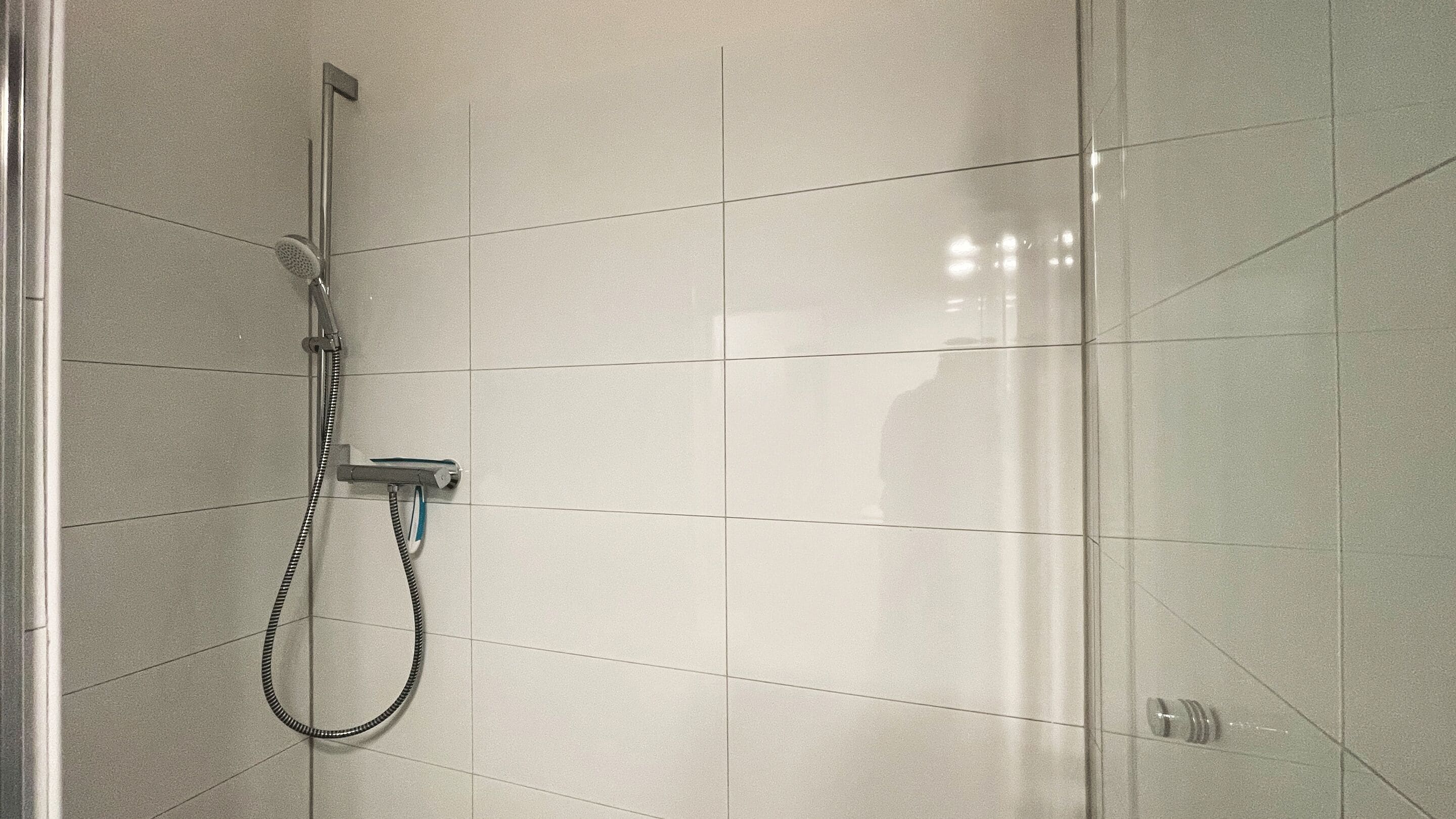 Un espacio con ducha, un cabezal de ducha de mano y un grifo instalado en la pared.