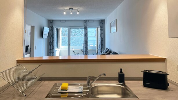 A modern kitchen with a stainless steel sink, a toaster, and a drying rack. - Schönes Apartment in Melle I home2share (Melle)