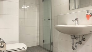 A modern bathroom with a toilet, a glass shower enclosure, and a sink with a mirror above it. - Schönes Apartment in Melle I home2share (Melle)