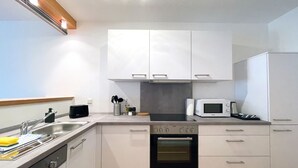 A modern kitchen with white cabinets, a built-in oven, a microwave, and a sink. - Schönes Apartment in Melle I home2share (Melle)