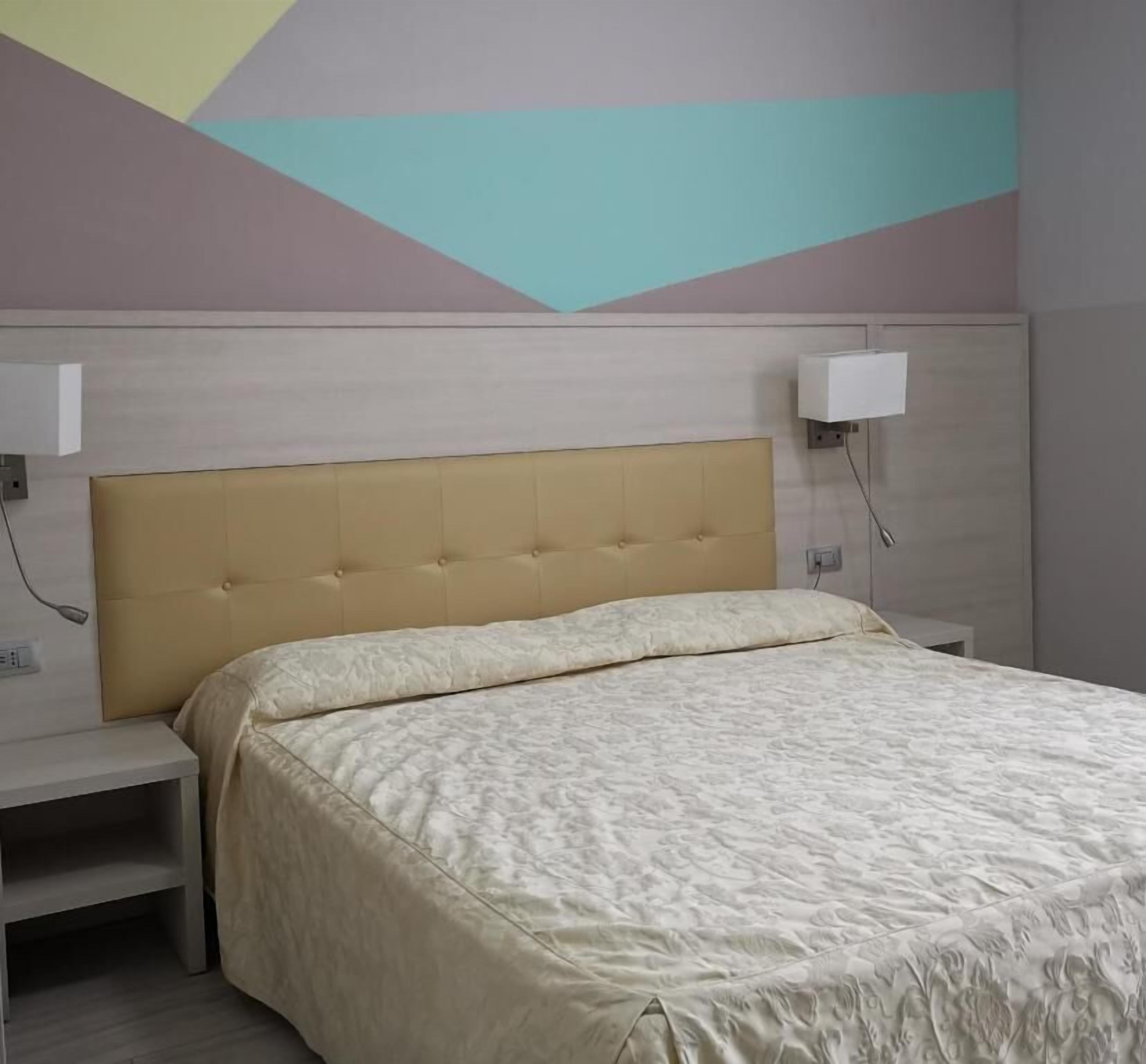 Un dormitorio con cama, mesita de noche y lámpara de pared.