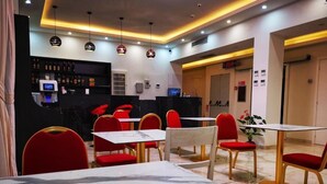 A restaurant with red chairs and white tables, a bar area with shelves of bottles, and a digital clock displaying the time. - CSI Group - Hotel metropoli (Milan)