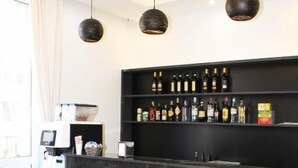 A modern bar area with a black marble countertop, two red bar stools, and a wine rack above. - CSI Group - Hotel metropoli (Milan)