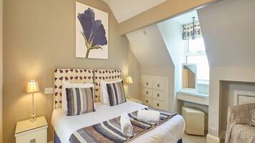 A bedroom with a large bed, bedside tables, a mirror, and a ceiling light fixture.