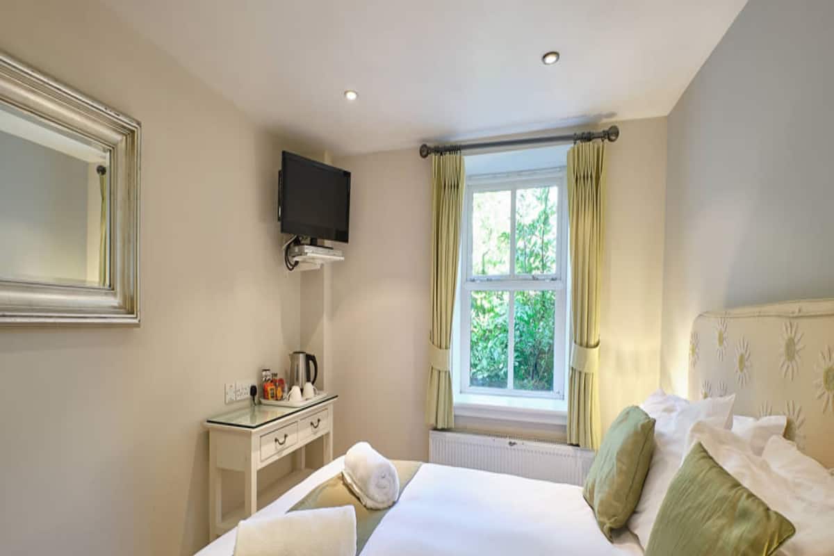 A hotel room with a bed, a desk, a television, and a window with curtains.
