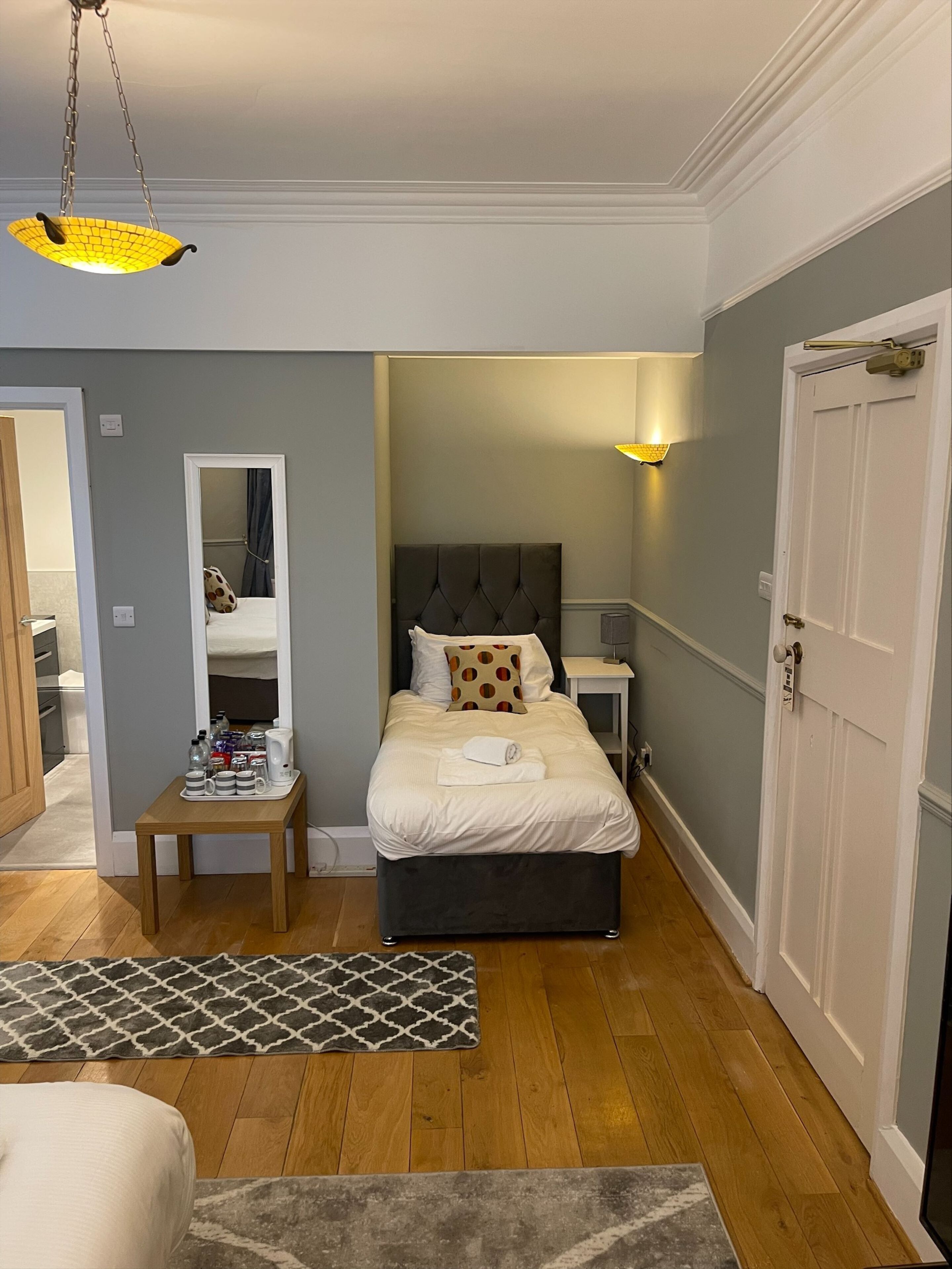 Quarto com cama, mesa de cabeceira e luminária suspensa.