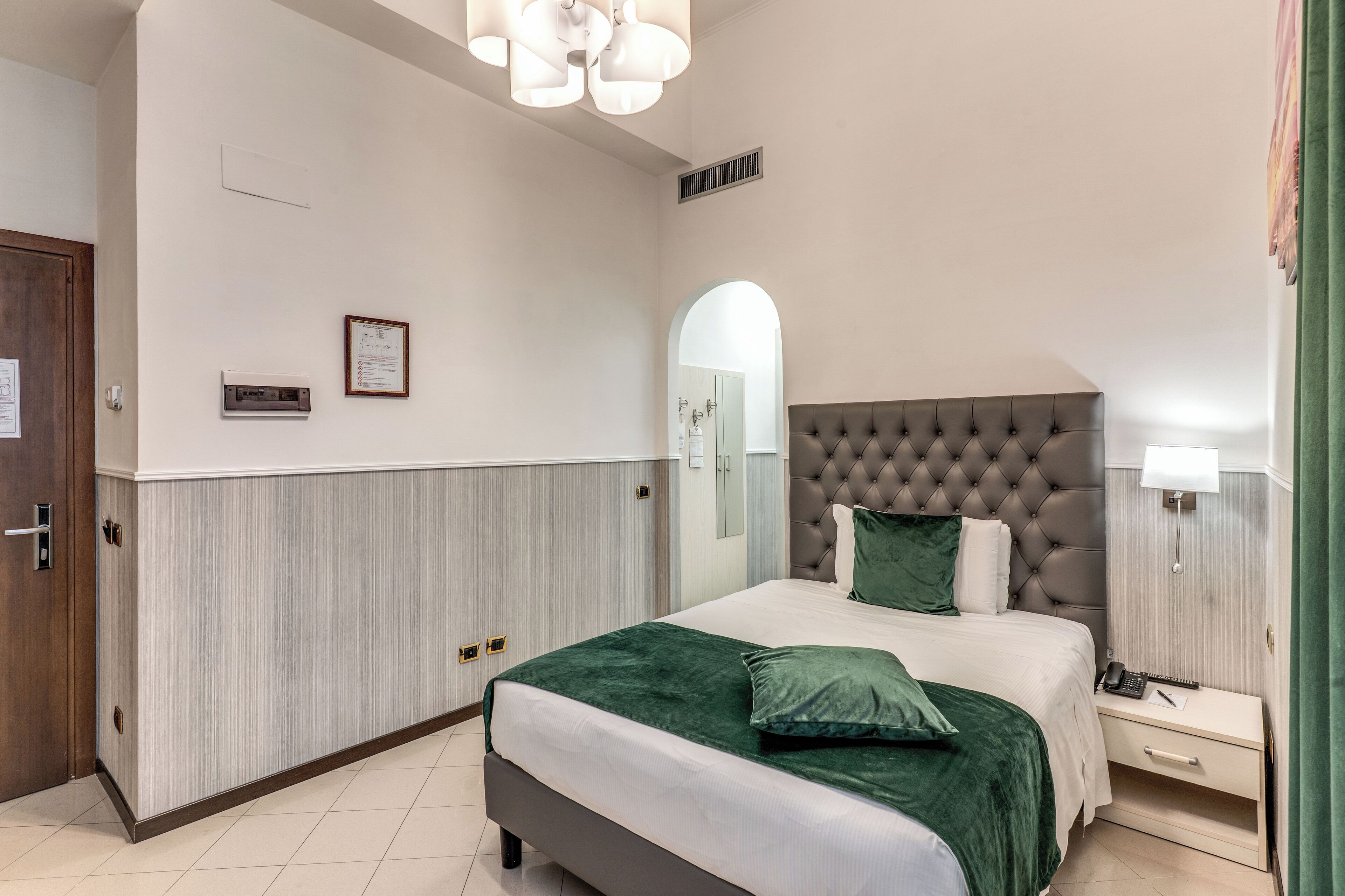 Un dormitorio con una cama grande, una mesita de noche, un espejo y una puerta.