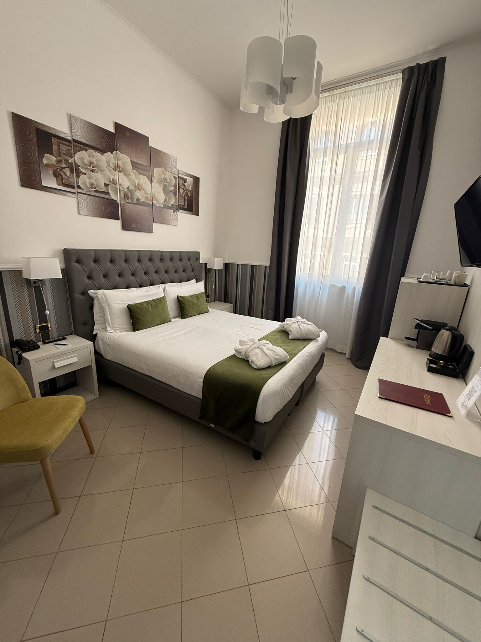 Une chambre d’hôtel moderne, dotée d’un grand lit, d’un bureau, d’une chaise et d’œuvres d’art accrochées au mur.
