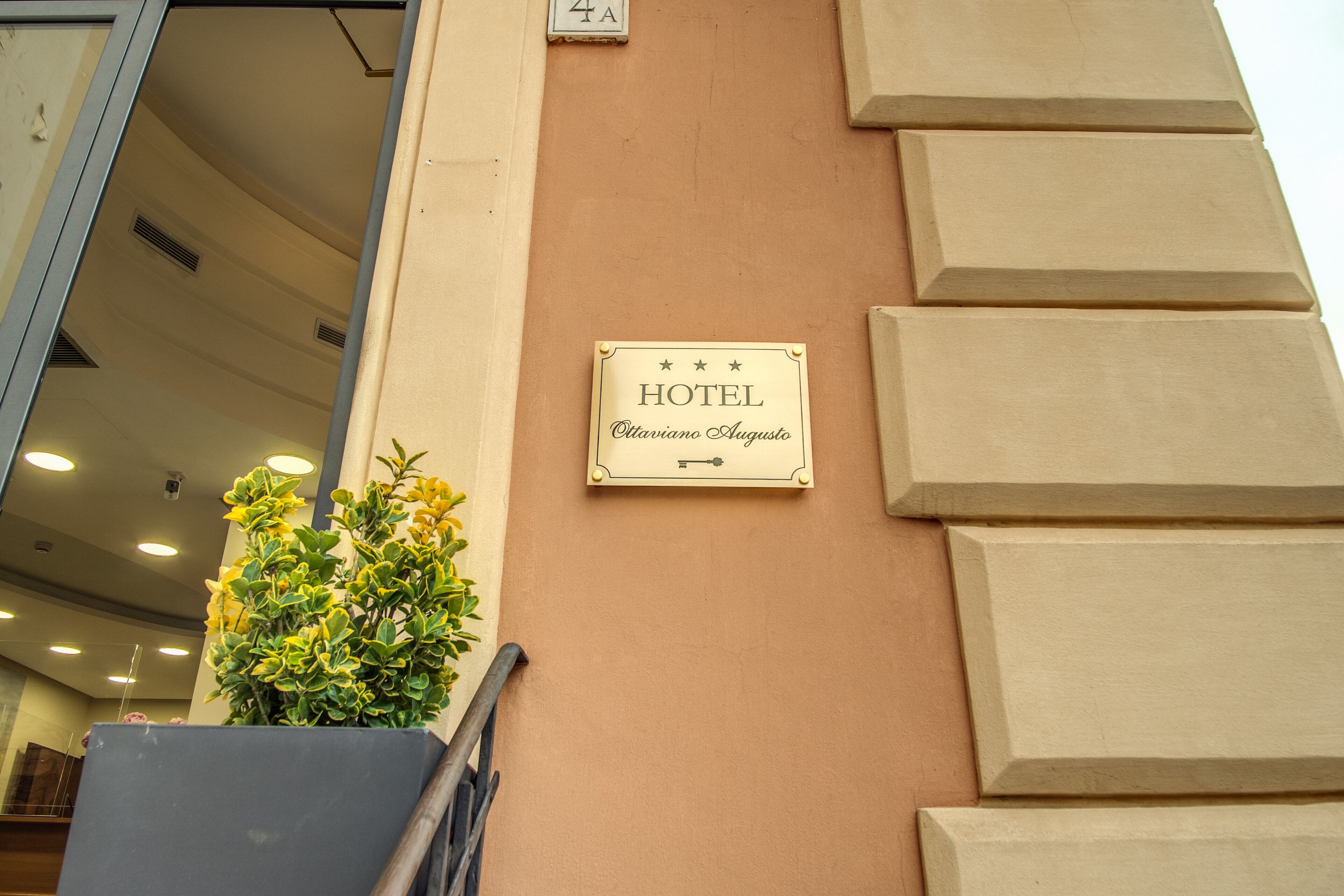 Un letrero de hotel con el nombre 'Ottaviano Augusto' en una pared color crema.