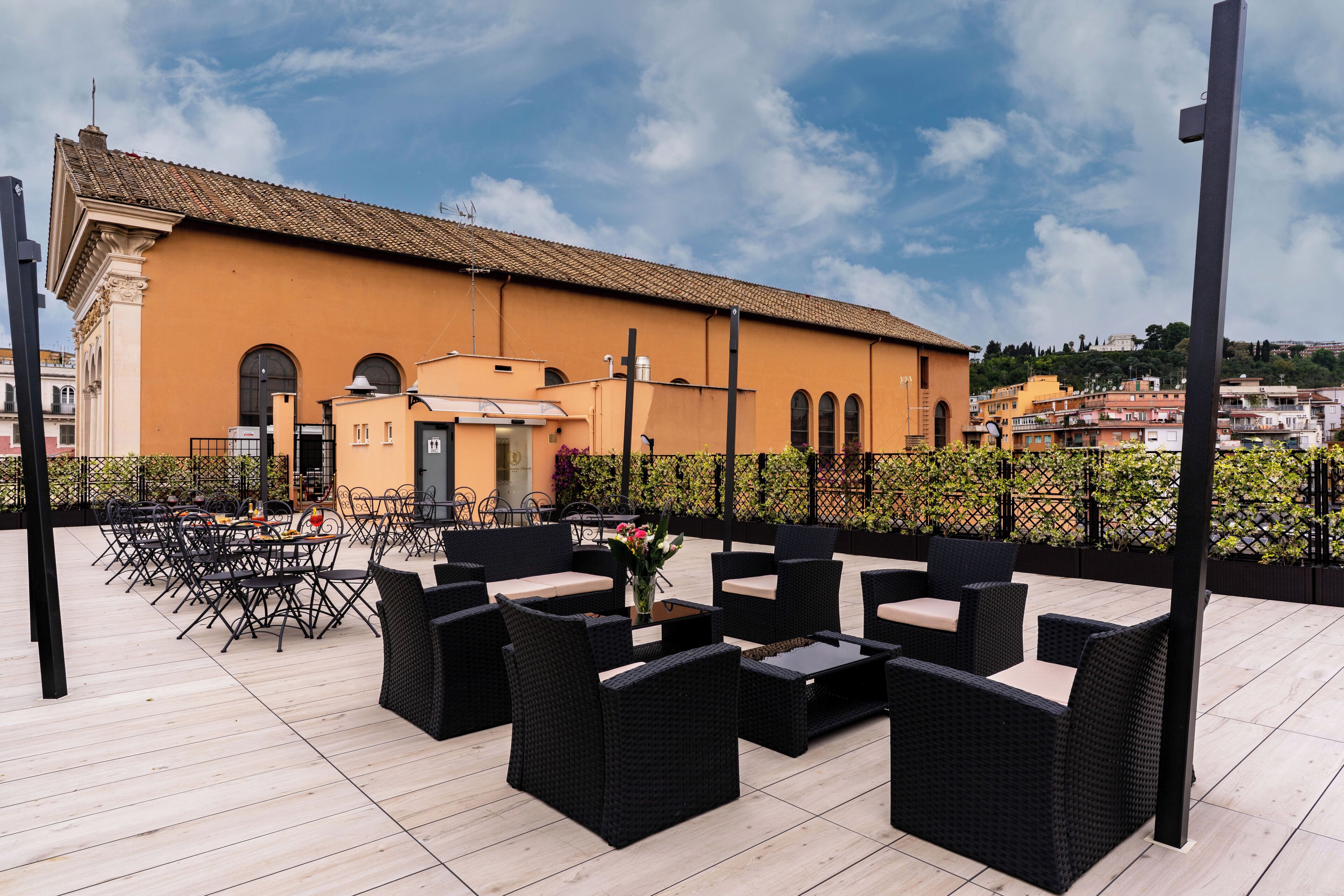 An outdoor patio with wicker furniture and a view of a building with a tiled roof.