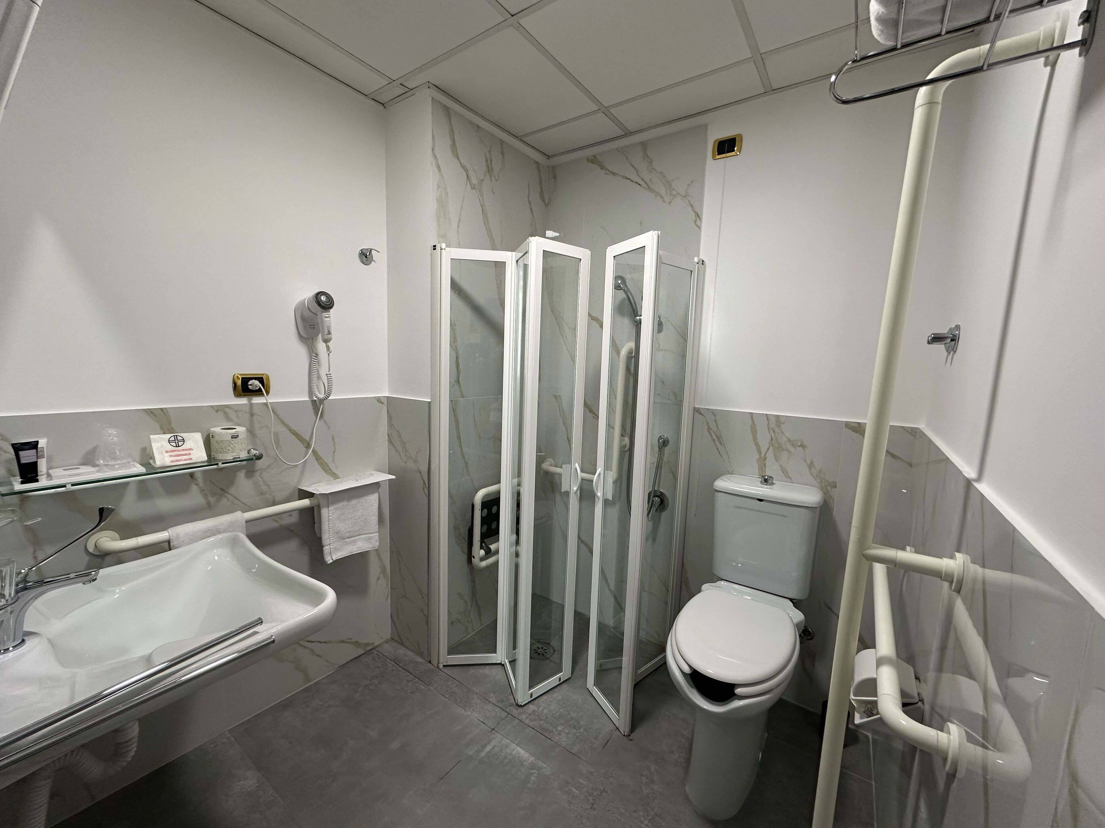 Un baño moderno con ducha envuelta en cristal, un lavabo blanco y un inodoro.