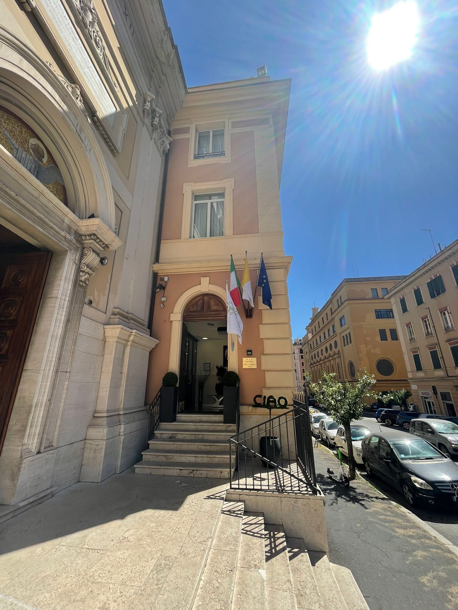 A building with a grand entrance, steps leading up to it, and flags on the facade.