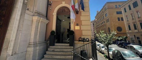A building with a grand entrance, steps leading up to it, and flags on the facade.