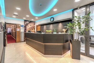 En moderne reception med en buet disk, et ur og en stor potteplante.