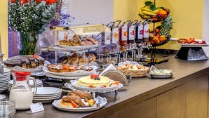 A buffet with various food items, including cakes, pastries, and a fruit display. - Hotel Ottaviano Augusto (Rome)
