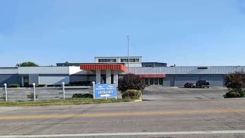 A Howard Johnson's BARMONT entrance with a parking lot and a building with a red awning.