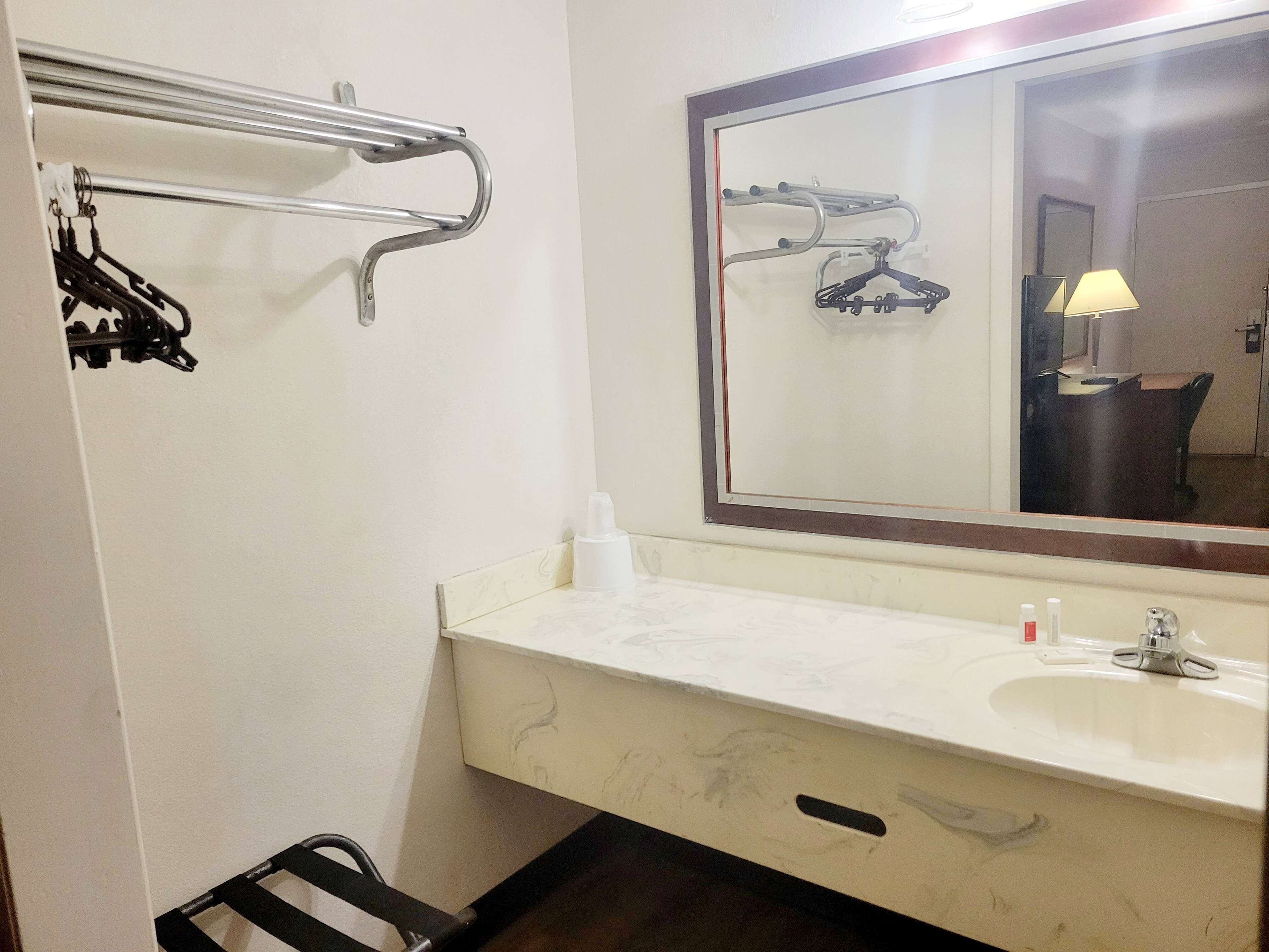 A bathroom with a white sink, a mirror, and a towel rack.
