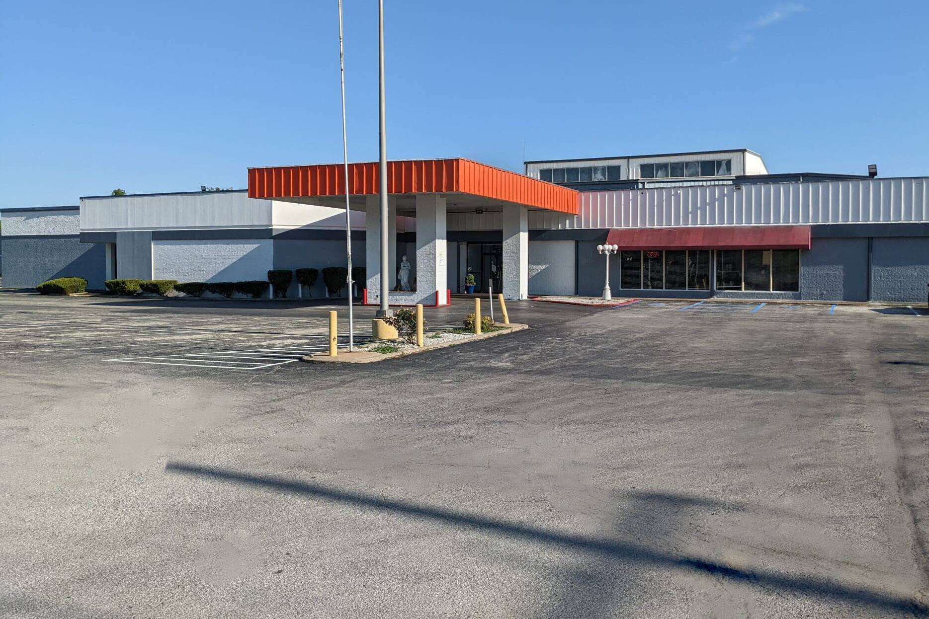 A gas station with a red canopy, a clear sky, and a parking lot.