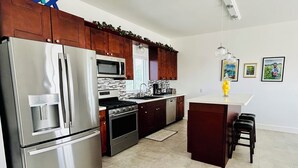 Cozinha moderna com eletrodomésticos de aço inoxidável, armários de madeira e uma ilha central.