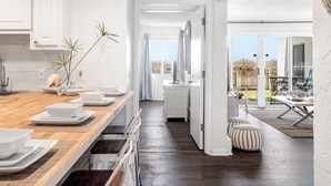 A modern kitchen with a wooden countertop, white cabinets, and a view to an outdoor patio.