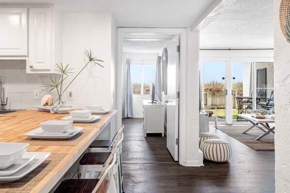 A modern kitchen with a wooden countertop, white cabinets, and a view to an outdoor patio.