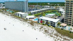 A coastal hotel with multiple buildings, a swimming pool, and a beach area.