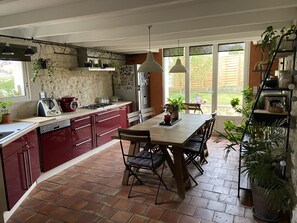 A kitchen with red cabinets, a wooden dining table, and various plants.