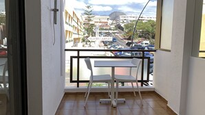 A balcony with a table and chairs, overlooking a street with parked cars and buildings. - Nice Apartment Playa Las Vistas. Free Wifi (Arona)