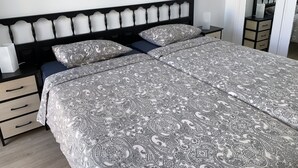 A neatly made bed with patterned bedding, a bedside table with a lamp, and a dresser with drawers. - Nice Apartment Playa Las Vistas. Free Wifi (Arona)