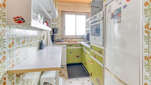 A kitchen with a tiled backsplash, a window, and a refrigerator with magnets. - Panoramic view of Paris (Paris)