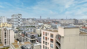 A cityscape with modern buildings, including a distinctive tower and the Eiffel Tower in the distance. - Panoramic view of Paris (Paris)