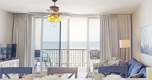 Enjoy a sea view from the balcony, featuring a large window, sofa, and table with chair.