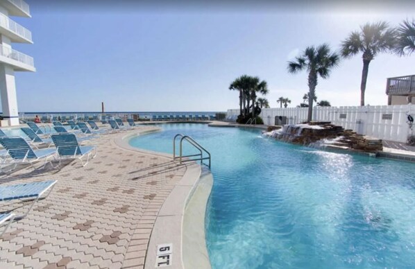 Relax by the pool surrounded by palm trees and lounge chairs.