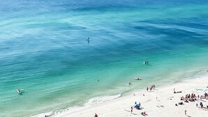 Ein Strand mit klarem türkisblauem Wasser, einem Sandufer und Menschen, die verschiedenen Aktivitäten nachgehen.