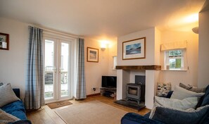 Una sala de estar con chimenea, televisor y sofá.