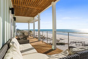 A covered outdoor seating area with a wooden ceiling, white pillars, and a view of the beach. - 4 Palms: 6 Bedrooms, Beachfront, Private Pool (St. George Island)