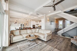 Ein geräumiges Wohnzimmer mit einer Eckcouch, einem Couchtisch und einer Treppe, die zu einer oberen Ebene führt.