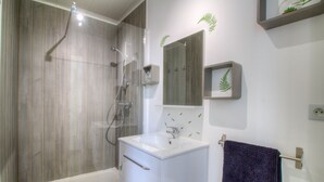 Un baño con ducha, lavamanos y espejo.