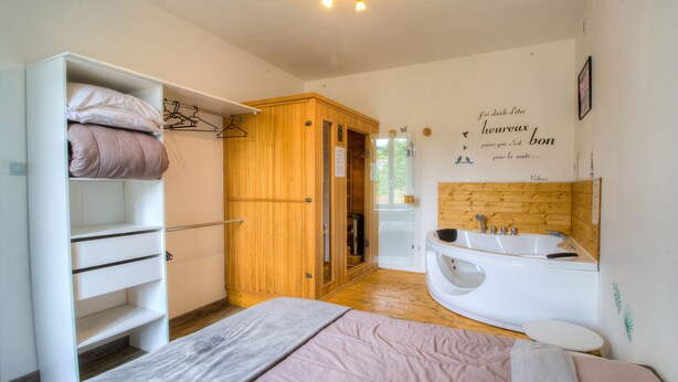 Un dormitorio con cama, armario de madera, baño con bañera y ducha.