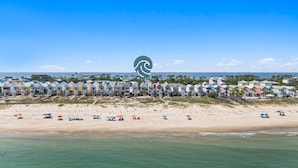 A beachfront hotel with colorful buildings, a sandy beach, and the ocean. - Above the Dune: 3 Bedroom, Beachfront, Sleeps 8 (St. George Island)