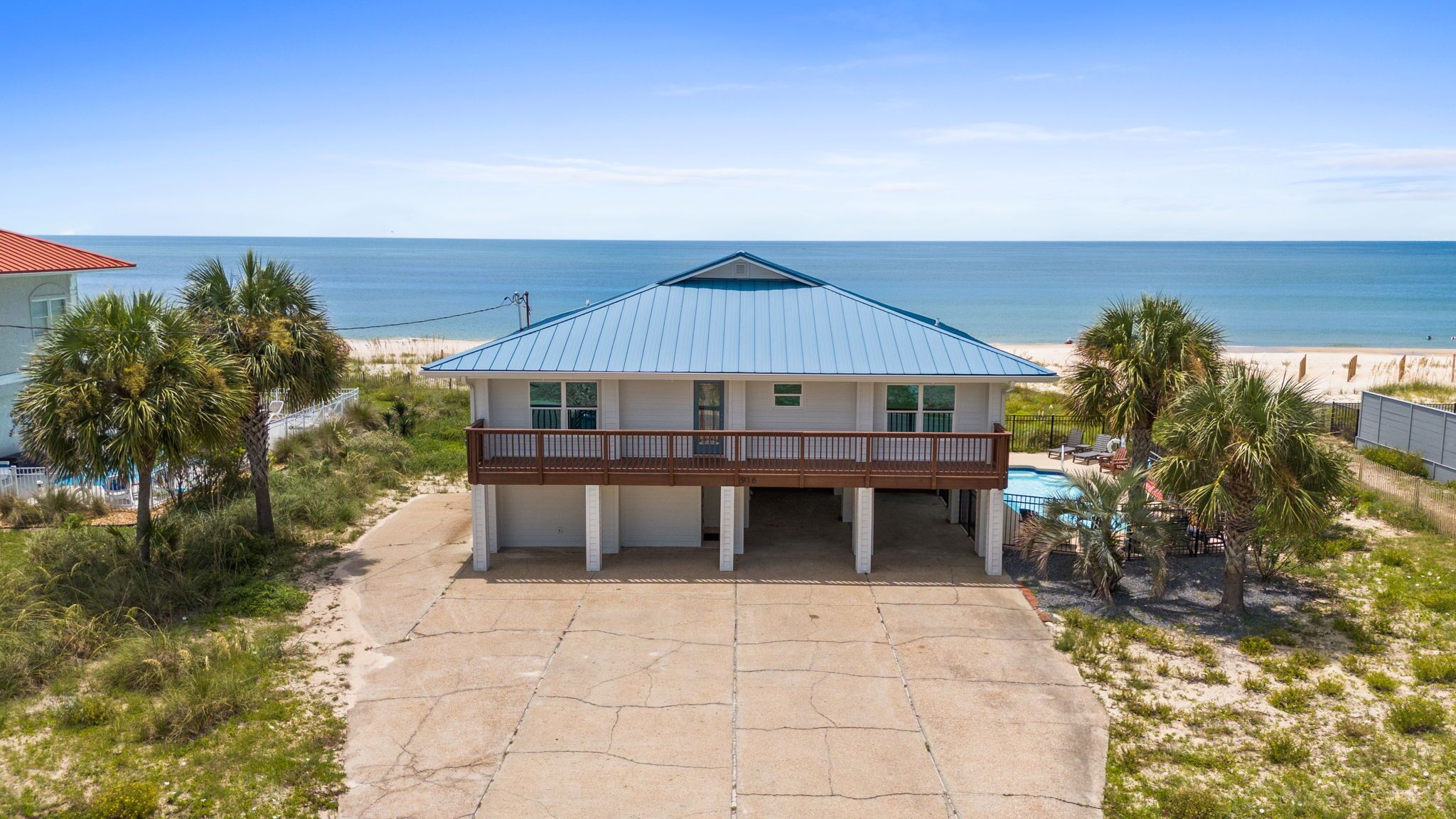 A beachfront house with a balcony, a swimming pool, and a view of the ocean.