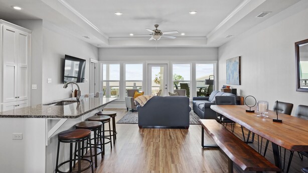 A spacious kitchen with a large island, bar stools, and a dining area with a wooden table and benches. - Blue Skies: Gulf Views, Private Pool, Pet Friendly (St. George Island)