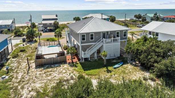 A beachfront property with a two-story house, a covered patio, and a view of the ocean. - On the Half Shell: Beach View, Private Pool, One level Home (St. George Island)