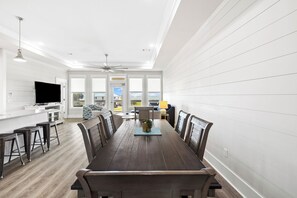 A spacious dining area with a long wooden table, multiple chairs, and a ceiling fan.
