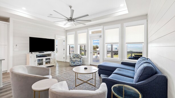 Un salon moderne avec un ventilateur de plafond, un grand téléviseur et un canapé.