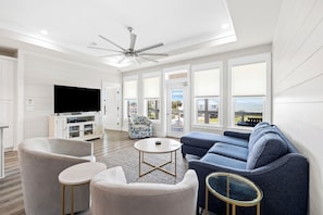 A modern living room with a ceiling fan, a large TV, and a sofa.